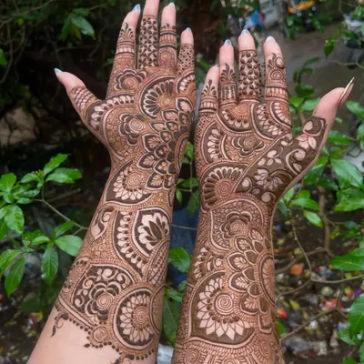 A stunning example of full coverage bridal mehandi. This design features large, intricate mandalas and paisley patterns that flow from the fingertips all the way up the arms.