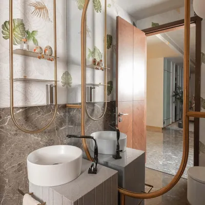 This powder room is an oasis of calm, featuring a custom stone vanity and a large, elegantly framed mirror. The nature-themed wallpaper and delicate metal shelving add layers of texture and sophistication, creating a memorable experience for guests.