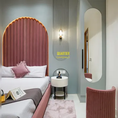 This daughter's bedroom at Apex D'Rio is a dream in pink and grey. The arched, tufted headboard is the star, complemented by a dedicated dressing area with a full-length mirror and a matching fluted stool.