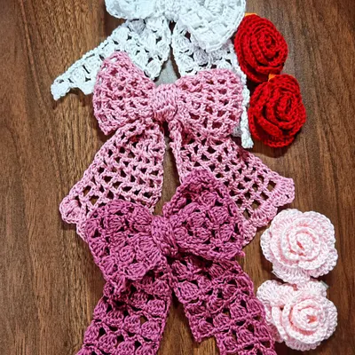 A beautiful collection of my handmade crochet hair accessories. This set includes large, elegant bows in different shades of pink and white, alongside red and pink rose hair clips.