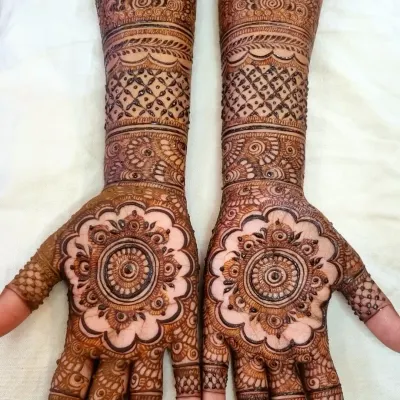 A gorgeous and intricate design for the bride's sister. The central mandala on the palm is a classic choice, surrounded by detailed patterns that extend up the forearm.