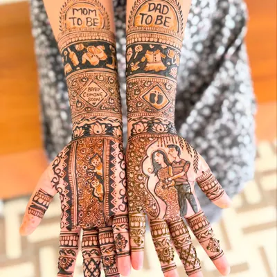A special mehendi for a baby shower, with "Mom to be" and "Dad to be" written on the wrists and a portrait of the expecting couple.