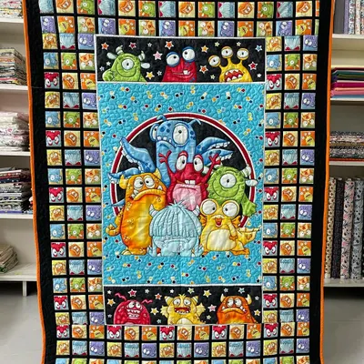 A fun and colorful "Monsters" themed quilt, perfect for a child's bedroom. The central panel features a group of friendly monsters, surrounded by a border of smaller monster faces.