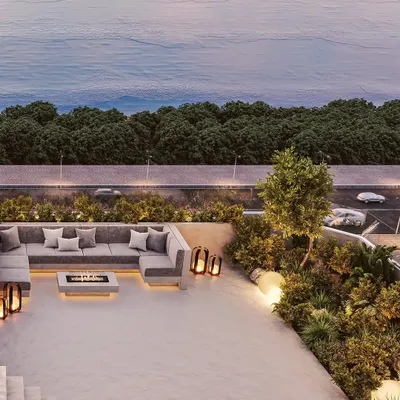 This private terrace opens up to the stunning Mumbai skyline and the sea beyond. The design features a comfortable, modern sectional sofa and a central fire pit, creating an inviting space for evening gatherings.