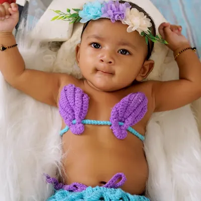 Our little mermaid theme is a favorite among parents. Here is a beautiful baby girl in a hand-knitted mermaid costume, complete with a floral headband.
