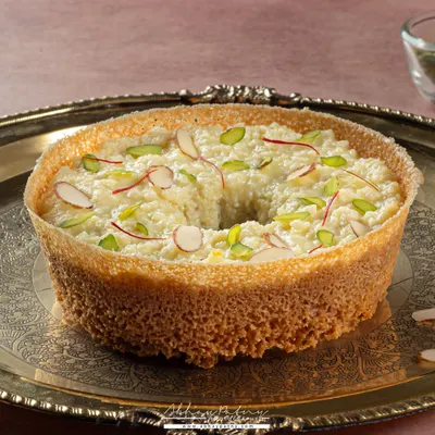 Ghewar is a festive delicacy, and I wanted to capture its royal feel. I used a traditional silver platter and soft lighting to highlight the intricate, porous texture and the delicate almond and saffron garnish.