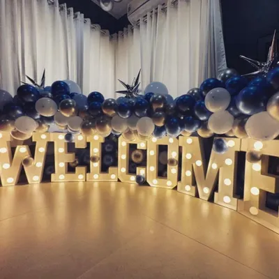 Make a bold statement with our large, light-up "WELCOME" marquee letters. Paired with a simple blue and silver balloon garland, this setup creates an exciting and festive entrance for any welcome home party.