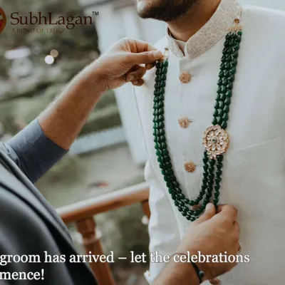 A groom gets help adjusting his emerald green necklace, a final touch to his wedding sherwani. We ensure our grooms feel confident and ready for their big day.