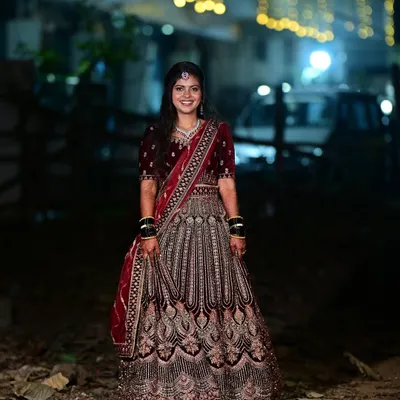 This bride is glowing for her reception. The deep red velvet lehenga is complemented by a soft glam makeup look and an elegant hairstyle, perfect for an evening celebration.