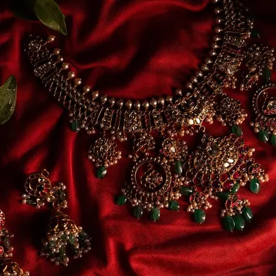 A close-up of the stunning temple jewelry, laid out on rich red silk. This detailed shot highlights the craftsmanship and beauty of the traditional bridal accessories.