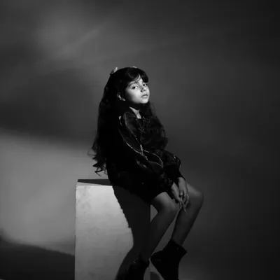 A dramatic black and white shot for a child's portfolio. The lighting and pose create a high-fashion feel, showcasing her ability to convey a serious and focused mood on camera.