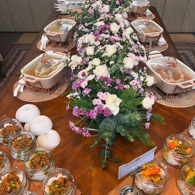 A full view of an elegant buffet table we set up for an intimate gathering. The spread includes our signature jar salads, multiple main courses in beautiful ceramic dishes, and a stunning floral centerpiece.