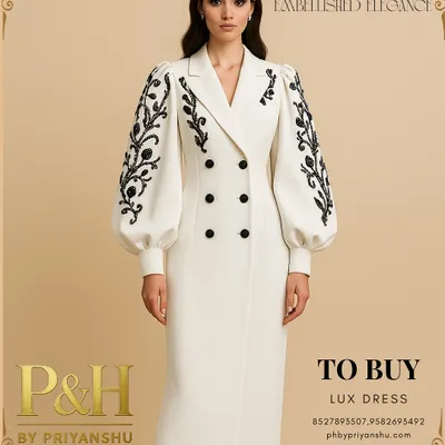 A vision of modern regality, this image showcases a model in a pristine white, double-breasted dress. The design is distinguished by its dramatic puff sleeves adorned with intricate black floral embroidery.