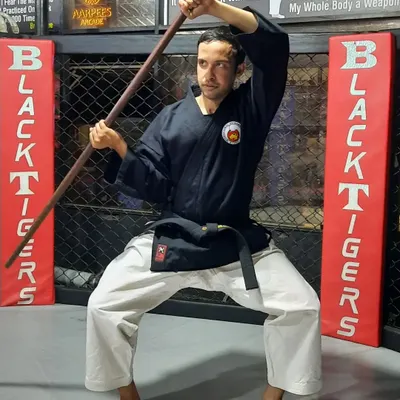 A strong foundation in Bo staff training begins with a stable, low stance. This image shows the proper grip and posture required for generating power and maintaining control during kata practice.