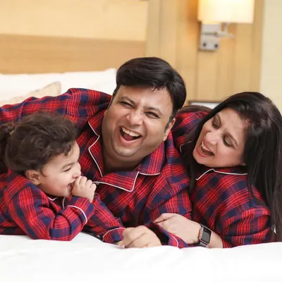 A family shares a big laugh while relaxing on the bed in matching pajamas. These are the real, joyful moments we aim to capture during our at-home lifestyle shoots.