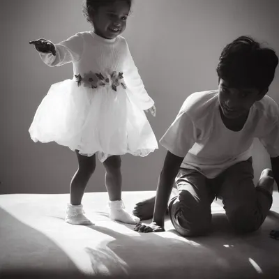 I love capturing the pure, uninhibited joy of childhood. This black and white photograph shows a young girl mid-jump on the sofa, a moment of pure energy and happiness during a natural family moments photography session at her home in Bangalore.