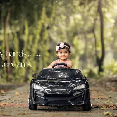 Tiny hands and big dreams. This little girl is ready to drive off into a world of adventure in her toy car during this beautiful, sunlit outdoor session.