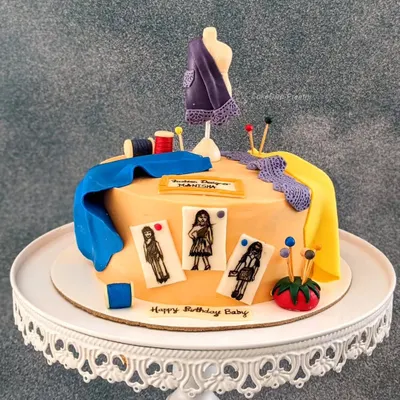 My first cake for a fashion designer! The design features a mannequin, bolts of fabric, and hand-drawn fashion sketches (croquis) on fondant, all edible.