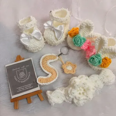 This custom gift set was made for baby Sree Vaishnavi. It includes personalized booties, a floral hairband, and a keychain with her initial 'S', all coordinated in beautiful pastel colors.