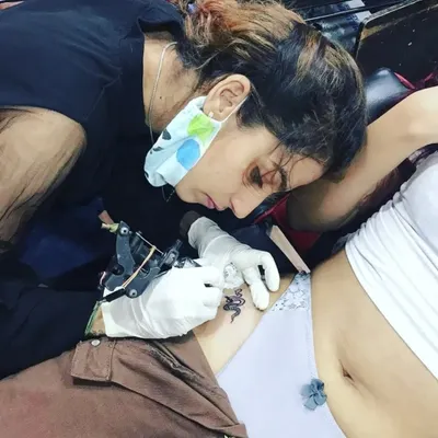 You learn by doing. This image shows a student getting practical experience, carefully tattooing a client in my studio. This is the core of my teaching method.