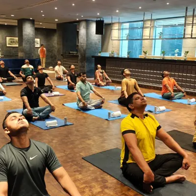 A corporate yoga session in progress, with employees practicing neck stretches to relieve tension from long hours at the desk. These simple movements can make a huge difference in preventing chronic pain and improving posture.