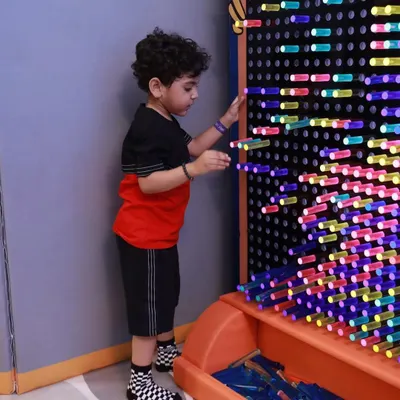 A young boy creating patterns on our interactive light wall. This giant pegboard is a fantastic tool for creativity, color recognition, and fine motor skills.