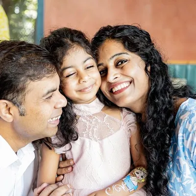 A happy squeeze from mum and dad. This candid family photo from a birthday party is full of genuine smiles and affection. It's these in-between moments that often become the most cherished memories.