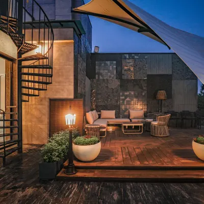 The terrace at our Vikaspuri project, featuring a spiral staircase, a custom stone-paneled wall, and a comfortable outdoor lounge area perfect for evenings.