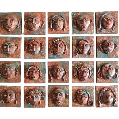 A complete set of 20 mini bronze faces laid out before installation. Each sculpture is unique, with different expressions and features, creating a collection of characters that feel both ancient and alive.