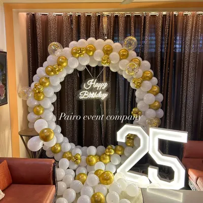 A classic white and gold balloon ring with a 'Happy Birthday' neon sign and '25' marquee numbers, perfect for a milestone celebration at home.