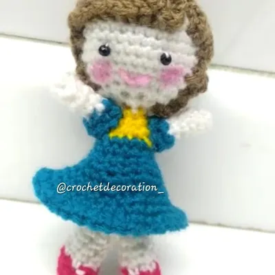 This sweet crochet doll was customized for a client, complete with brown hair, a blue dress, and pink shoes. We can create personalized dolls based on photos or descriptions to make a truly one-of-a-kind gift.
