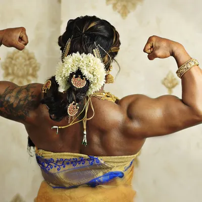 A view of the results of dedicated back and shoulder training, framed by a traditional silk saree and jasmine flowers. This pose highlights the sculpted muscles of my upper back and deltoids.