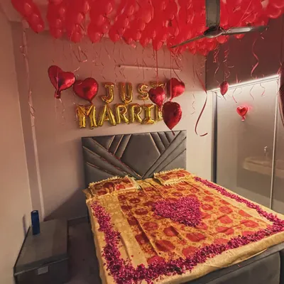 A classic 'Just Married' room decoration to welcome the newlywed couple. The ceiling is filled with red balloons, with gold foil 'Just Married' balloons on the wall. We also decorated the bed with a heart shape made from fresh rose petals for a special romantic touch.