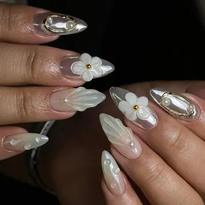 An intricate set featuring 3D sculpted shells, pearls, and transparent floral elements. This level of detailed work is what we practice in the advanced nail art course.