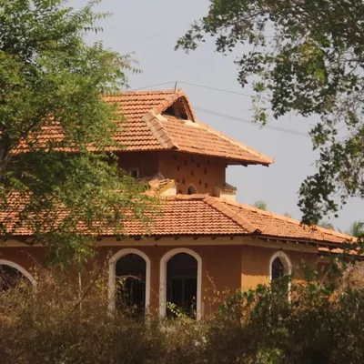 The Doddaballapura mud house nestled among the trees. Its earthy tones and traditional form make it feel as if it has always been a part of the landscape.