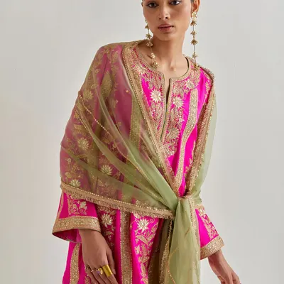 A bold statement in fuchsia and olive green. This model showcases a stunning kurta with all-over gold embroidery, uniquely styled with a contrasting dupatta tied as a belt.