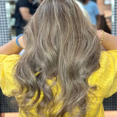 These cool-toned ash blonde highlights are perfectly blended into the base color. This look is achieved through meticulous placement and toning to neutralize any brassiness.