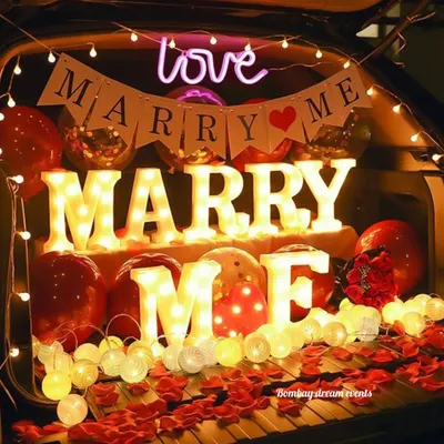 The perfect surprise proposal. This car boot decoration features 'MARRY ME' marquee letters, a neon sign, balloons, and rose petals for a truly romantic gesture.