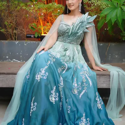 Feel like a character from a fairytale in this stunning ombre gown. The color fades from sea green to deep blue, adorned with silver embroidery and a flowing cape for a touch of magic.