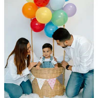 A first birthday is a celebration for the whole family. Including parents in the hot air balloon setup creates a beautiful portrait of shared joy and adventure on this special day.