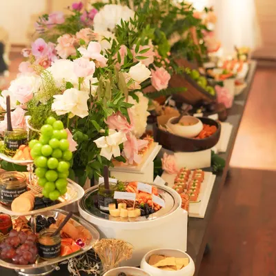 A closer look at our magnificent grazing table, showcasing tiers of fresh Kumaoni grapes, artisanal cheese platters, and an array of delicate canapés. The composition is designed to invite guests to explore a variety of flavors and textures.