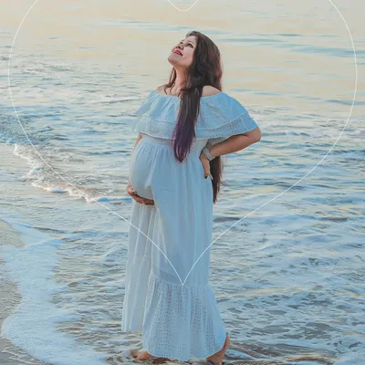A serene solo portrait of a mom-to-be standing in the gentle ocean surf. The natural setting adds a sense of calm and wonder to this outdoor maternity photo.