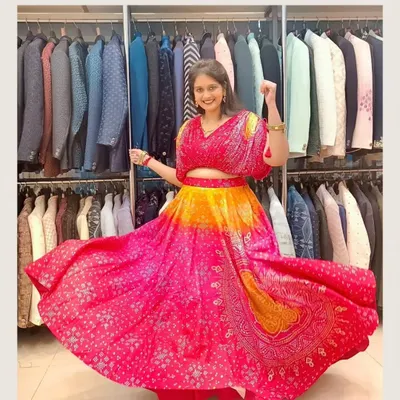 Twirl into the celebration with this vibrant pink and orange lehenga. The bandhani-inspired print and flowy skirt make it a fun and festive choice for a sangeet or mehendi.