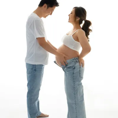 The look of pure joy and anticipation. This candid moment from a minimalist studio maternity shoot captures the real, unfiltered connection between two people.