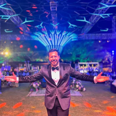 Welcome to the celebration. Dressed in a tuxedo and ready to host a spectacular Sangeet night under a stunningly decorated venue. This is where I make the magic happen.