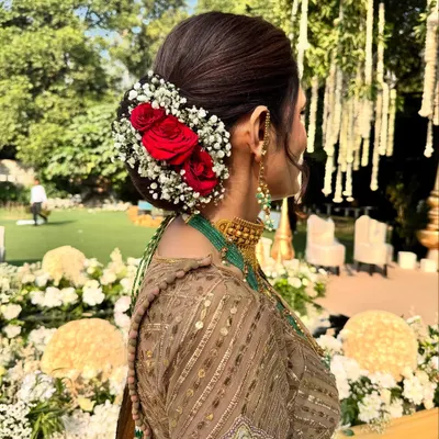 A close-up of the elegant floral bun we created for the mother of the groom. Fresh red roses and baby's breath make for a timeless and classic wedding hairstyle.