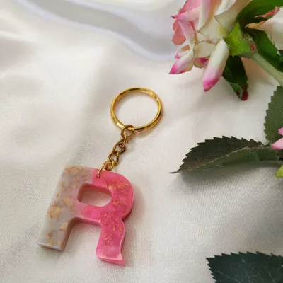 A custom initial keychain made with a beautiful blend of pink and pearl white resin, with a touch of gold flakes for sparkle.