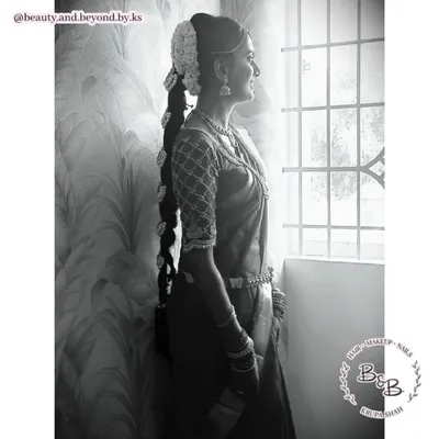 This black and white photo beautifully captures the timeless elegance of a South Indian bride. Her traditional long braid, or Jadai, and perfectly draped saree create a silhouette that is classic and graceful.
