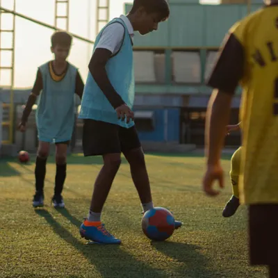 The sun sets, but the training continues. A young player practices close ball control, a fundamental skill we emphasize in every session to build confidence and composure on the ball.