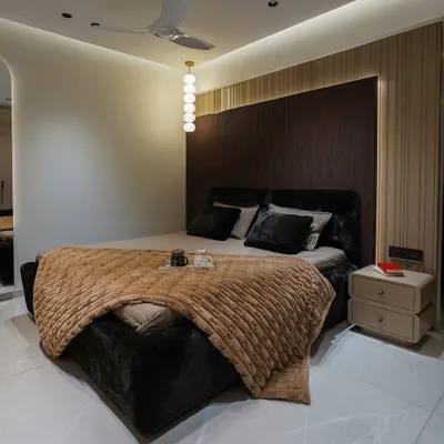 A complete view of a modern luxury bedroom. The design features a dark, textured headboard wall with fluted paneling, a custom upholstered bed, and integrated cove lighting for a moody and sophisticated ambiance.